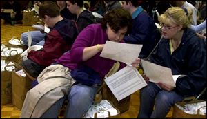 Carrie White, left, and Sarah Hart study their routes during a meeting in Calvary Assembly of God's gym.