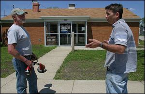 Mayor Richard Teeple, left, talks with resident Tom Kern, who is upset at the announced closing of the Bradner branch of the Wood County Public Library, in the background. The mayor was trimming weeds around the building, which the village owns.