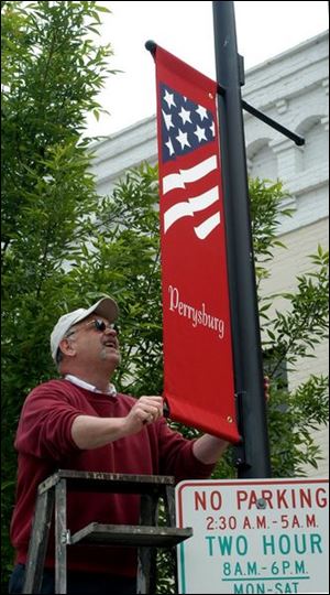 nbr photo by don simmons may 23, 2003   lloyd swanson streets and public bldings operations supervisor for the city of perrysburg hangs one of the new banners at the intersection of 2nd st and louisiana ave in  downtown perrysburg
