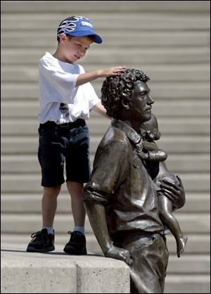 ROV art 01 - C. J. Austin, age 5, son of Karin Austin of Toledo, touches the statue that is in the ampatheater area of COSI during a lunch hour with St. Catherines Summer Day Camp. Toledo Blade/Allan Detrich