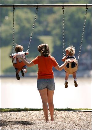 ROV swinging 01 - L-R, Tyler Kristufek and his twin sister Taylor, both 2, are pushed on a swing set by their mother Lauryl, in Walbridge park. Toledo Blade/Allan Detrich