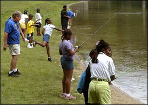 Volunteers help teach fishing at Olander Park as part of the National Youth Sports Program.