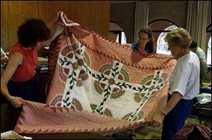 From left, Catherine Lewis, Anne French, and Mary Clark look over the raffle quilt for the Kaleidoscope of Quilts show. Quilters piece together beautiful biennial show