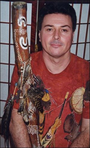 Phil Jones cradles his didgeridoo, which is decorated with aboriginal symbols and is made from a piece of eucalyptus tree hollowed by termites.