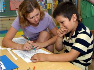 Lourdes College junior Charla Bender works at York Elementary with Luis Baltazar, 6, one of more than 130 students enrolled in a program for the children of migrant workers.