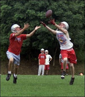 Bowsher football players Jake Myers and Colin Rossi reach for the ball during a passing drill. 