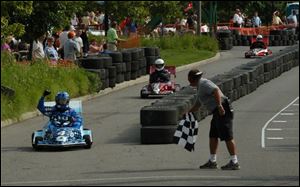 EARLY VICTOR: Giving the checkered flag to Doug Brimmer, driver of Dana car No. 4, is Jason Sanderson, flagman during one of the heats in the 2003 Grand Prix race at Owens Corning World Headquarters Saturday.
