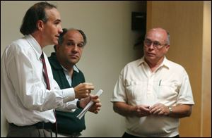 Michael Beazley, clerk of City Council, explains the procedure to Chuck Cassis of Chuck's Sports Bar and Bill Delaney of Delaney's Bar, from left at left.