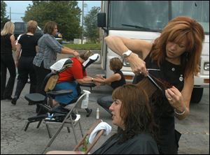 Karen Hazelton cuts Evelyn Duncan's hair in the parking lot of the Cherry Street Mission as part of Project Daymaker. The program, which came to the mission for the first time last year, offers free haircuts and stress-relieving massages to the homeless and to low-income families.