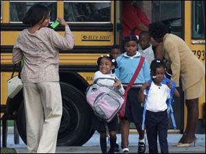CTY TPS12P 4 8/12/03 PHOTO BY LORI KING Stephanie Smith takes a photo of her daughter, Kayla, pink and grey bookbag, as the kindergartner gets off the bus for her first day of school at Old West End Academy.