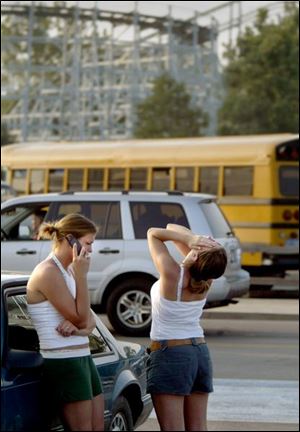 Colleen Shank and Shannon Daughtery, both of Cleveland, wait in the parking lot of Cedar Point during the electric outage that affected northern Ohio and other states.