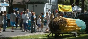 Nbr the crowd goes past a giant ear of corn that was a float in the parade. ( I was late getting there as I had another earlier job.)  blade photo by herral long  8/23/2003