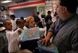 Howard Cherry, a fourth-grade teacher at Thurgood Marshall Elementary School, collects workbooks from students in his all-male classroom in Seattle.