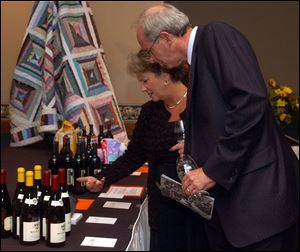 FINE WINE: Joyce and Jerry Johnson, owners of the Vineyard, look at some of the wine to be auctioned at the fourth annual Taste of the Vine at Gladieux Meadows.
