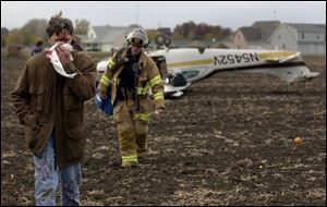 Dr. Richard Munk of Sylvania walks away from his plane with a broken nose after he made a forced landing in a field.