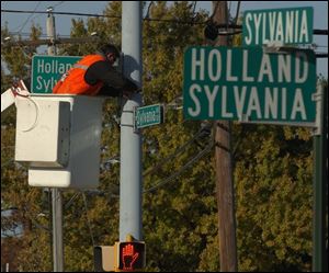 Dave Durfey installs a larger, more reflective road sign at the Holland-Sylvania and Sylvania Avenue intersection. Crews are replacing signs throughout Lucas County to help combat failing eyesight for seniors and other drivers.