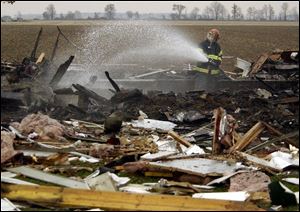 A McComb firefighter hoses down the debris left after an explosion leveled the 2,000-square-foot ranch-style home.