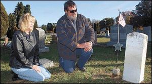 Sandy Komisarek and Bill Tunison, cemetery co-sextons, visit the grave of John Pelkey, a civil war veteran, in Springfield Township Cemetery.