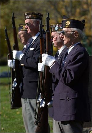 Members of the Lucas County Burial Corps wait to perform a military salute during a funeral at Calvary Cemetary.