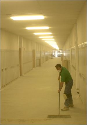 Shop foreman Rick Jackson is engulfed in dust as he sweeps a hallway of the new Gibsonburg High School before the floor is put down. Students are scheduled to move in after the Christmas break.