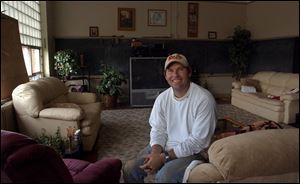 Scott Rood, in his living room, has renovated former classrooms and offices in the 89-year-old Liberty School into several apartments where he and family members live.