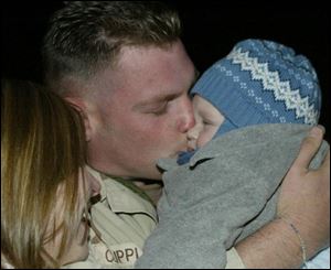 Sgt. Chad Cupples kisses his son, who was born after his deployment to Iraq eight months ago. His wife, Amanda, and the infant went to Pope Air Force Base to greet her husband.