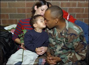 Sgt. Donnale Williams kisses Donnale, Jr., 2, as his wife Katherine and son Christopher, 11 (partially hidden), look on during a ceremony at Owens Community College yesterday for departing members of the 216th Engineer Battalion, Company C. Sergeant Williams departs for the Middle East later this month.
