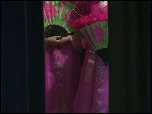 CTY KOREAN08P 2 1/8/03 PHOTO BY LORI KING Two of the dozen or so girls from the Kidz Chorale, of Korea, wait behind the stage curtain to be introduced for their performance during parent meeting at Toledo Christian School.