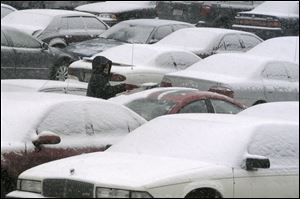 A women cleans snow from her car in a downtown Toledo parking lot before venturing out on slippery roads.