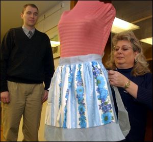 Deborah Di Gennaro adjusts an apron owned by Mamie Eisenhower and historian Mike McMaster helps.