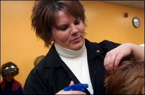 Holly Gors of Liberty Center, a Toledo Academy of Beauty Culture student, puts finishing touches on a haircut.