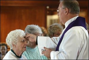 CTY ash25p 02- Rev. Joseph Keblesh, Jr. of the St. Matthews Episcopal church on Talmadge Rd. puts ash on the foreheads of his parishoners during an Ash Wednesday service. . Allan Detrich/The Blade