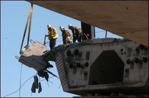 Crews remove a broken section of bridge segment from the new I-280 river crossing. Workers are continuing to clear debris from the site where four people died after a crane collapsed last week.