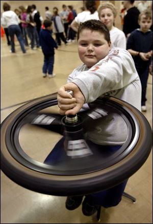 Travis Roach experiments with a gyroscope as the Toledo COSI on Wheels visits Jackman Road Elementary.