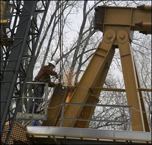 A workman cuts away a portion of the wrecked crane where four workers were killed and four others were hurt Feb. 16.