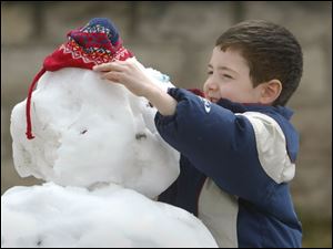 ROV snowman 01 - Samuel Pardi, 6, puts the the finishing touches on the snowman he and his mother Jodi made int he front yard of their Wood Street in Fremont. Allan Detrich/The Blade