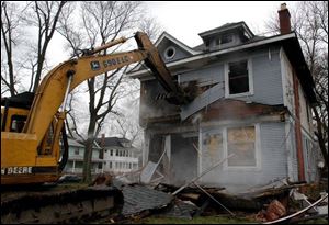 City crews begin tearing down a house at 2307 Warren St., the first of 250 scheduled to be razed this year.