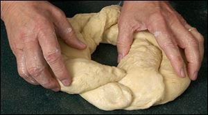 Rome Marinelli forms a loosely braided ring of dough.