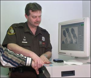 Monroe County corrections officer Dwayne Dobbs electronically scans fingerprints into a law enforcement database.