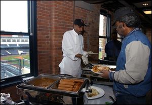 Mud Hens employee L.C. Bates, right, samples some of the new fare that will be availbale at Fifth Third Field. He is being served by Michael Satterfield of Gladieux Catering.