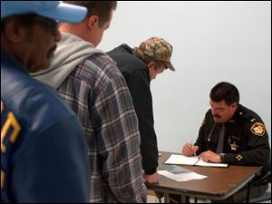 Lt. Greg Wojciechowski hands out applications in Lucas County yesterday to applicants for carry permits.