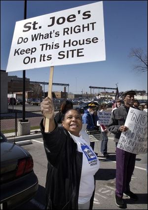 Alica Glover raises her sign at the Catholic Center on Spielbusch Avenue during a rally by a group opposed to moving Lathrop House from the  grounds of St. Joseph Church in Sylvania.
