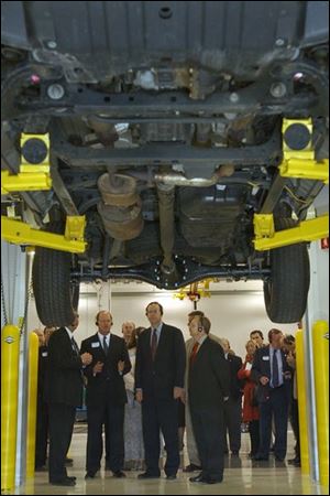 Gov. Bob Taft, center, is flanked by Dana executives as he examines the axle and driveshaft of a Toyota Tundra during his tour of the new Dana technical center in Maumee.