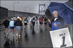 Ned Miklovic reads off times at the one-mile marker during the 28th annual Glass City Marathon. A field of 568 runners from the United States and Canada competed on the rain-slickened course, which began in Toledo and headed south to Rossford, Perrysburg, and Maumee before returning to finish in downtown Toledo.
