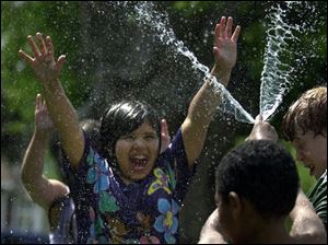 ROV COLD RELIEF 5/9/04 PHOTO BY LORI KING Kennedy Rios, 9, gets a blast of cold water from neighbor Stephan Robinson, 6, as they play with a hose on Colton St. in Toledo.