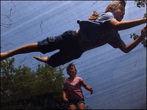 ROV FLYING HIGH 5/11/04 PHOTO BY LORI KING Aubrey Hazel, 5.5, watches her sister, Kristin, 7, dive on the trampoline in her aunt's Perrysburg, OH backyard.