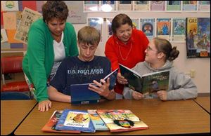 Idali Feliciano, center rear, director of Cambios, and eigth-grade teacher Ruth Lyons, left, help students Justin Fetzer and Amber Martin at Adrian's Sand Creek school with their reading. 
