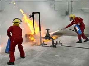 CTY May 11, 2004 - Steve Asmus, left, of the Anderson's in Maumee, and Ray Hixson of the West Alexandria, O. Fire Dept. and Rohm & Haas, an industrial chemical company in West Alexandria, learn to put out a gasoline fire with a dry chemical agent on equipment at the BP Oil Refinery Fire Field in Oregon.  They are participants in the State Fire School which is conducting some of it's training at the refinery.  Blade photo by Dave Zapotosky   CTY fire11p