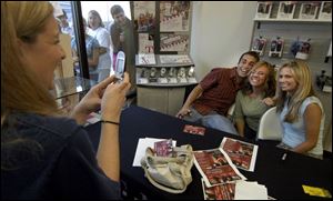 Kelly Stockner of Perrysburg takes a picture of her friend, Shannon Spencer of Perrysburg, flanked by 'Real World' stars Brad and Cameran at a T-Mobile store in Crossroads Centre.