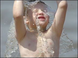 ROV swim 02 - Devin Mervine, 6, son of Brenda Mervine of Castalia, grimaces as he dumps water over his head at the Port Clinton public beach after getting water in his eyes. The warm weather had the beach quite crowded. Allan Detrich/The Blade
